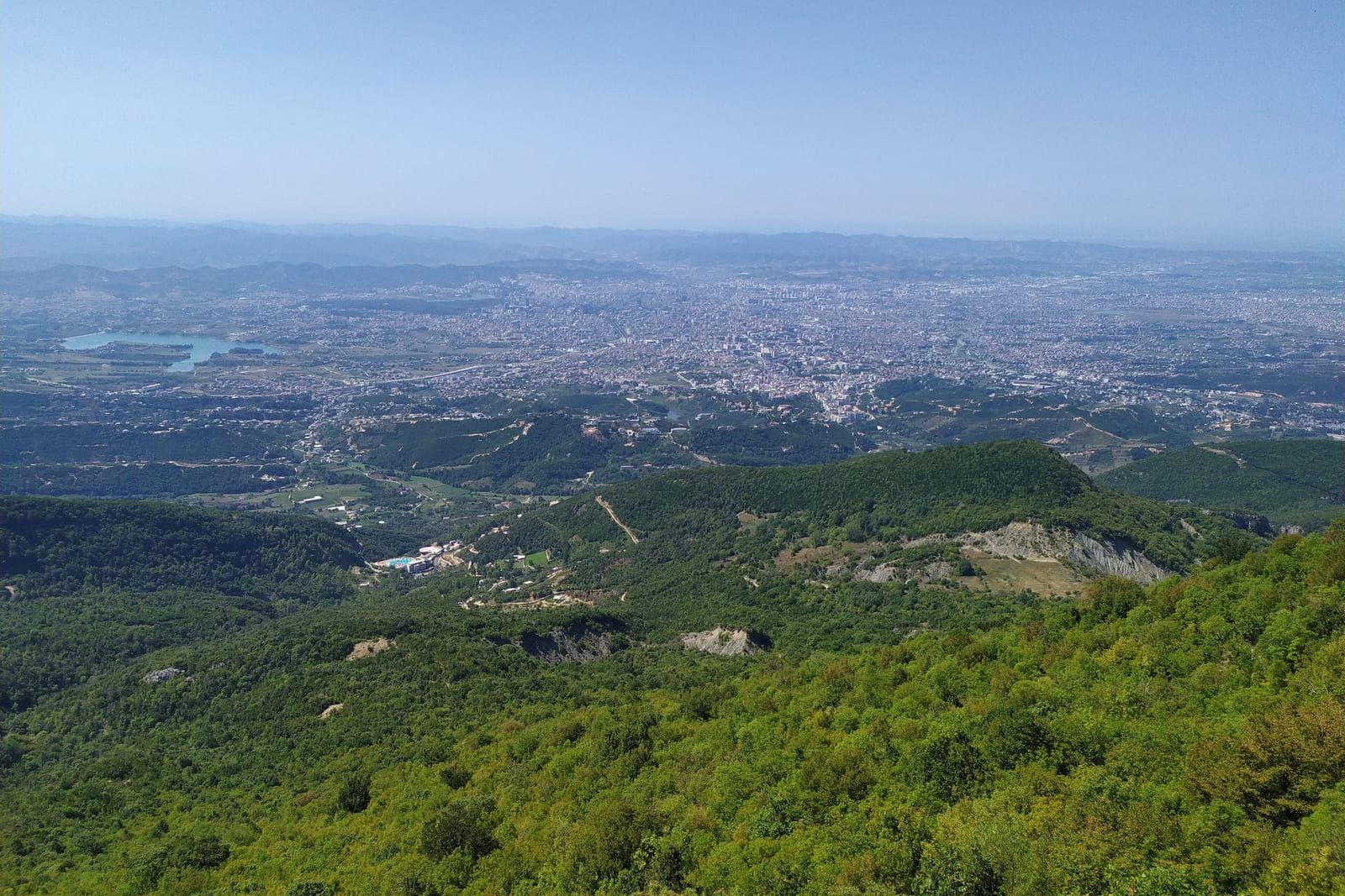 The city of Tirana spread across the plain below, seen from the green slopes of Dajti Mountain