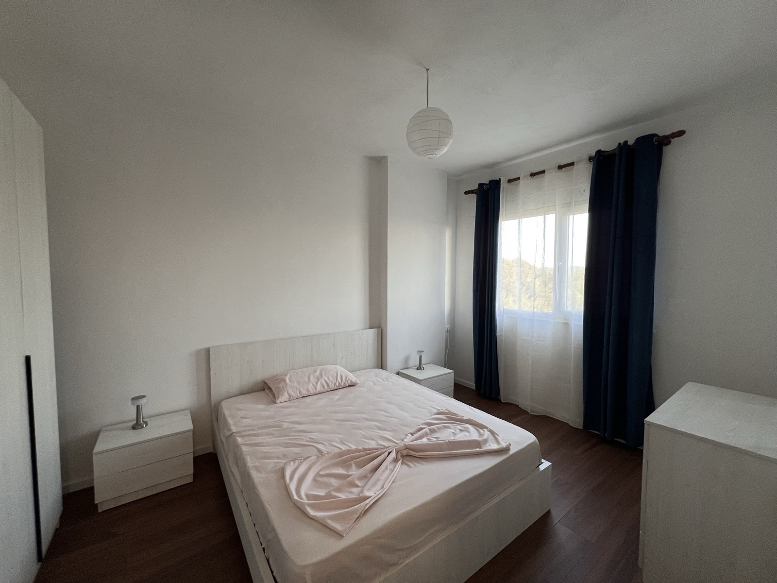 Double bedroom with blackout curtains, bedside tables and a leafy green outlook